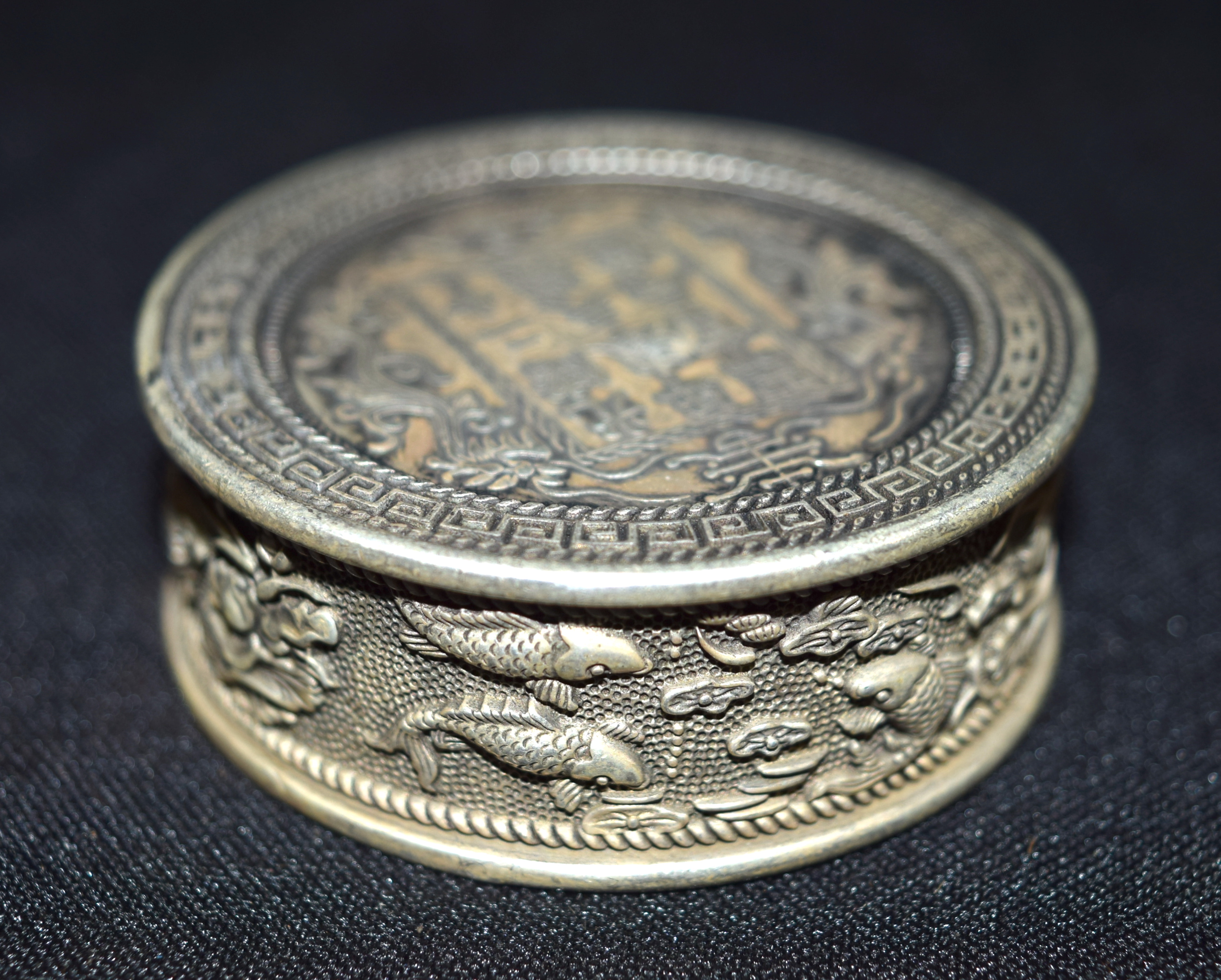 A Chinese white metal embossed coin box 5 x 2 cm