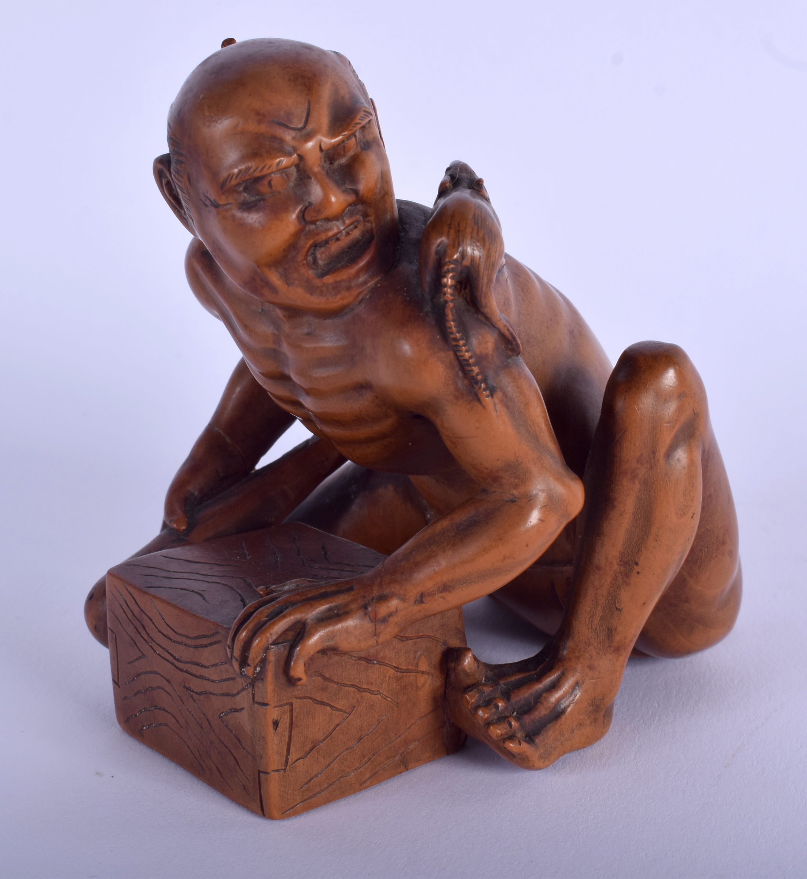 A 19TH CENTURY JAPANESE MEIJI PERIOD CARVED BOXWOOD RAT CATCHER modelled scowling upon an upturned