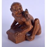 A 19TH CENTURY JAPANESE MEIJI PERIOD CARVED BOXWOOD RAT CATCHER modelled scowling upon an upturned