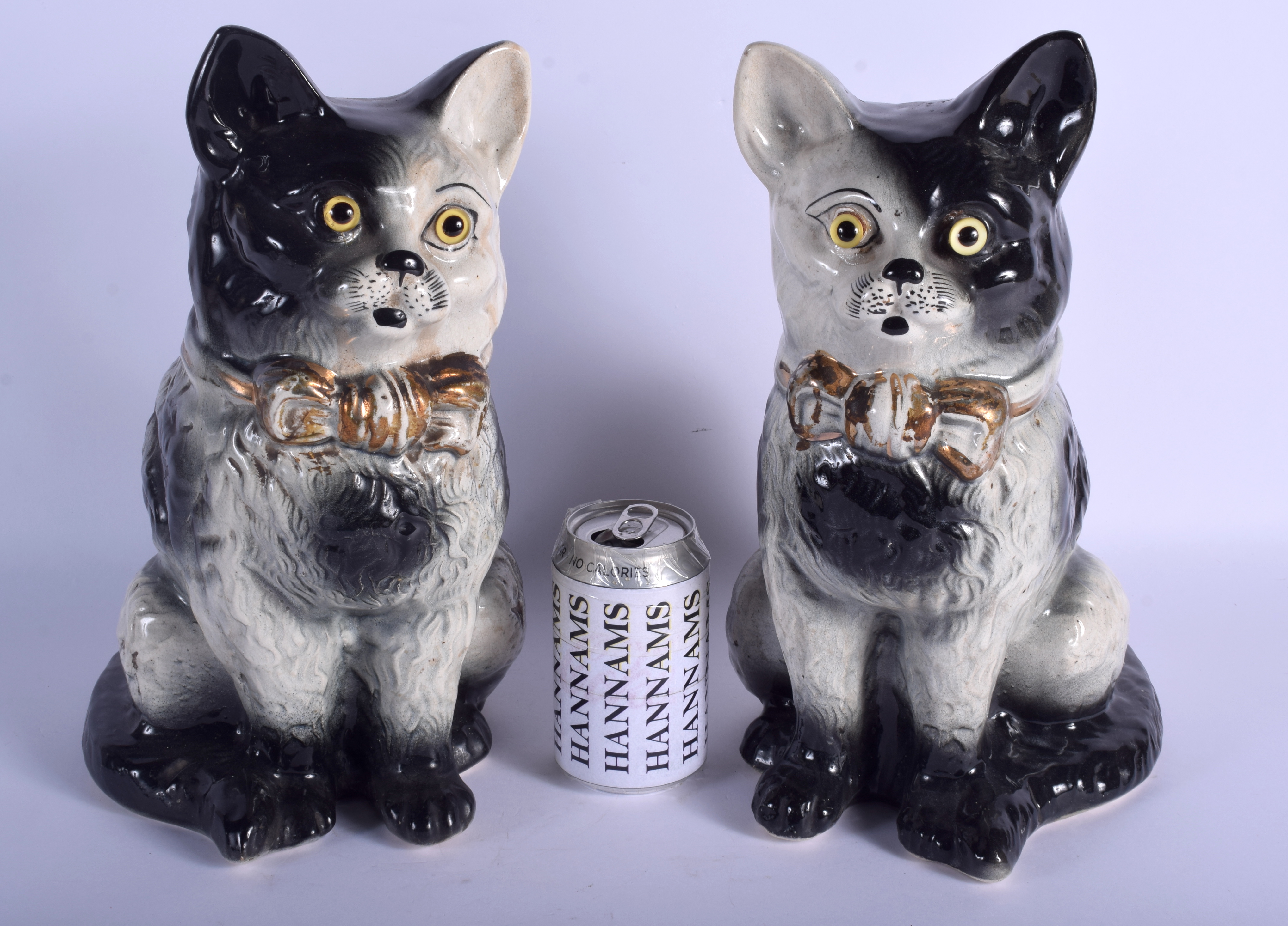 A LARGE PAIR OF 19TH CENTURY CONTINENTAL POTTERY CATS modelled in gilt bow ties. 34 cm high.