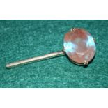 A large clear stone iridescent blue stone set in a yellow metal pin