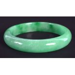 A CHINESE CARVED GREEN JADEITE BANGLE 20th Century. 7 cm diameter.