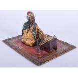 A 19TH CENTURY AUSTRIAN COLD PAINTED BRONZE FIGURE OF A SEATED MALE modelled upon a carpet. 12 cm x