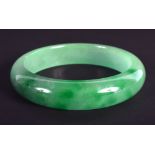 A CHINESE CARVED GREEN JADEITE BANGLE 20th Century. 7 cm diameter.