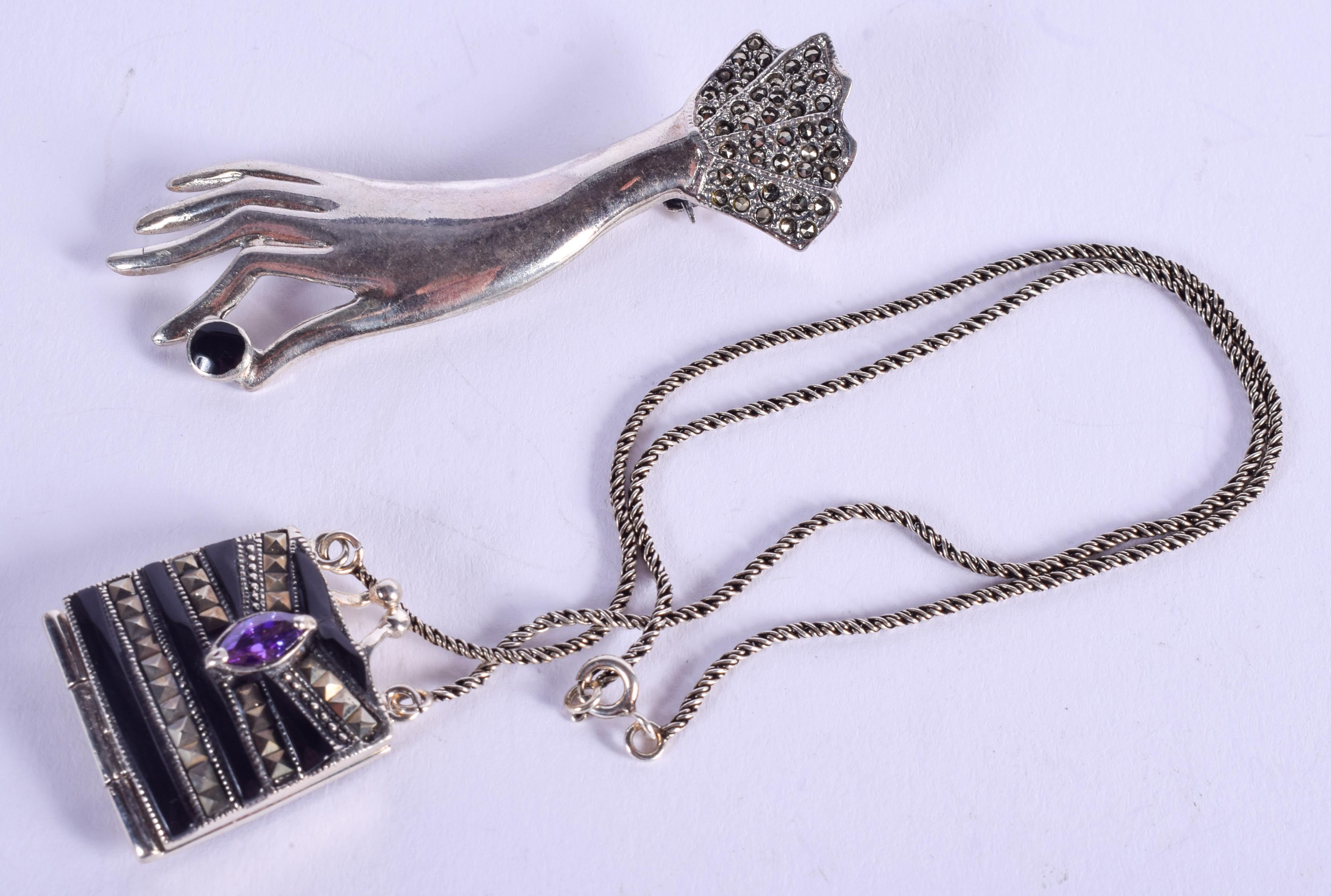 A SILVER PURSE and a silver hand brooch. Largest 6.5 cm wide. (2)