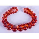 AN ART DECO ORANGE AMBER TYPE NECKLACE. 40 cm long, largest bead 1.5 cm.