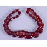 AN ART DECO CHERRY BEAD NECKLACE possibly amber. 53 grams. 56 cm long, largest bead 3 cm x 2 cm.