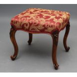 A VICTORIAN WALNUT DRESSING STOOL upholstered in a red and gold scrolling foliate weave, overstuffed