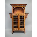 AN ARTS AND CRAFTS OAK BOOKCASE, the overhanging cornice on bracket supports, the frieze with