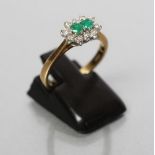 AN EMERALD AND DIAMOND CLUSTER RING, the two small emeralds claw set to a border of ten small