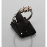 A THREE STONE DIAMOND RING, the graduated brilliant cut stones claw set to a plain white shank,