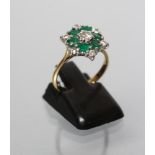 A DIAMOND AND EMERALD CLUSTER RING, the central diamond of approximately 0.20cts claw set to a