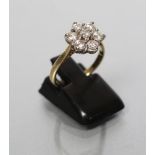 A SEVEN STONE DIAMOND CLUSTER RING, the round brilliant cut stones claw set to plain shoulders and