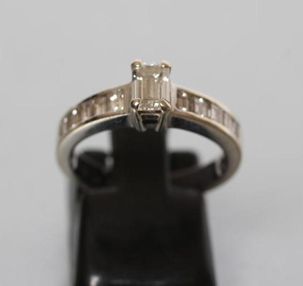 A DIAMOND RING, the baguette cut central stone of approximately 0.30cts claw set to shoulders each - Image 2 of 3