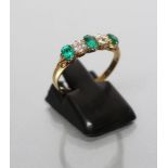 AN EMERALD AND DIAMOND FIVE STONE RING, the three oval facet cut emeralds claw set with two
