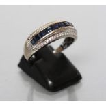 A SAPPHIRE AND DIAMOND HALF HOOP RING channel set with ten square cut sapphires with a border of