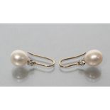 A PAIR OF PEARL EARRINGS, the slightly oval pearls drilled below a small round brilliant cut diamond