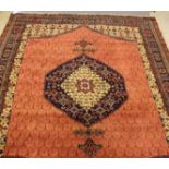 A PERSIAN STYLE CARPET, the madder field with repeating shield pattern in ivory and