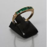 AN EMERALD HALF HOOP RING, the six square cut stones channel set to a plain shank, stamped 18k, size