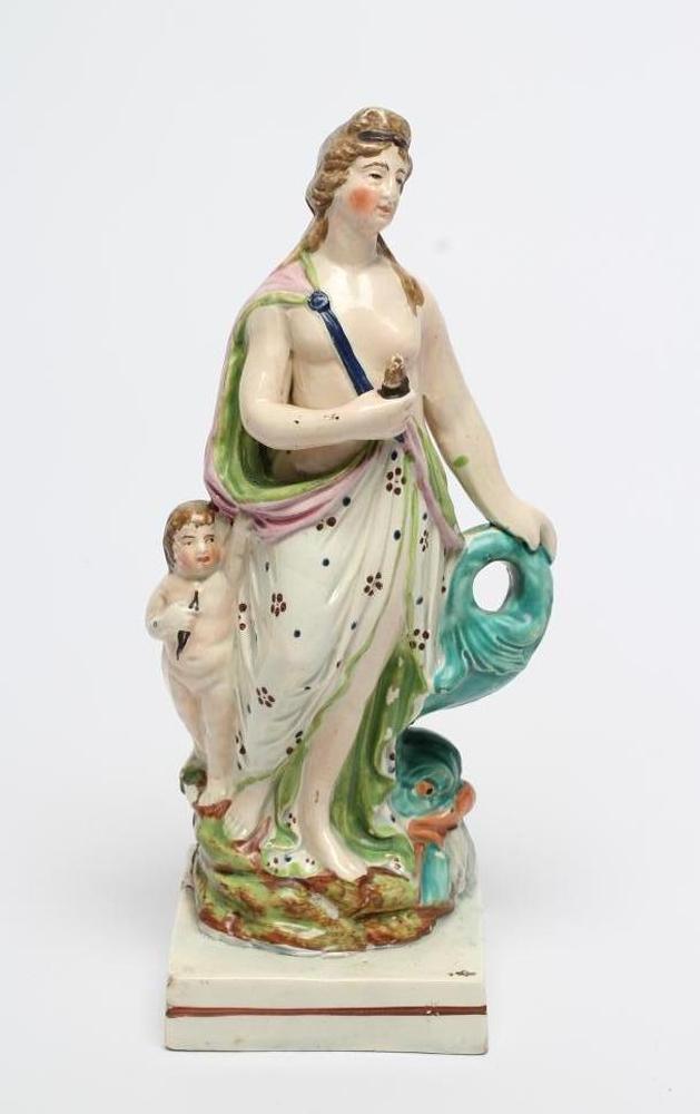 A POLYCHROME PEARLWARE FIGURE OF VENUS, c.1810, the semi-draped figure standing beside cupid and a