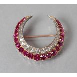 A RUBY AND DIAMOND CRESCENT BROOCH, the inner border pave set with nineteen graduated old mixed