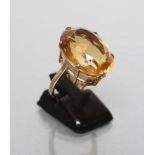 A CITRINE COCKTAIL RING, the oval facet cut stone claw set to a plain unmarked shank, size J (Est.