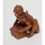 A JAPANESE WOOD OKIMONO carved as a rat catcher, the seated semi-naked man with a rat on his left