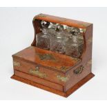 A LATE VICTORIAN OAK TRIPLE TANTALUS, the three hobnail cut spirit decanters with facet cut globular