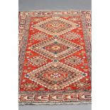 A PERSIAN TRIBAL RUG, modern, the bright red field with three linked hooked guls in blue, red,