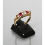AN EDWARDIAN FIVE STONE RUBY AND DIAMOND RING, the central cushion cut diamond flanked by two claw