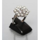 A CLUSTER RING, the nineteen brilliant cut cubic zirconia claw set to a plain 18ct white gold shank,