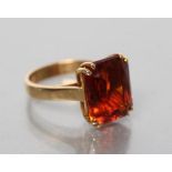 A COCKTAIL RING, the oblong cut dark citrine coloured stone claw set to a plain, wide, unmarked