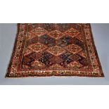 A WEST PERSIAN TRIBAL RUG, the field navy at either end with repeating floral gul pattern, the