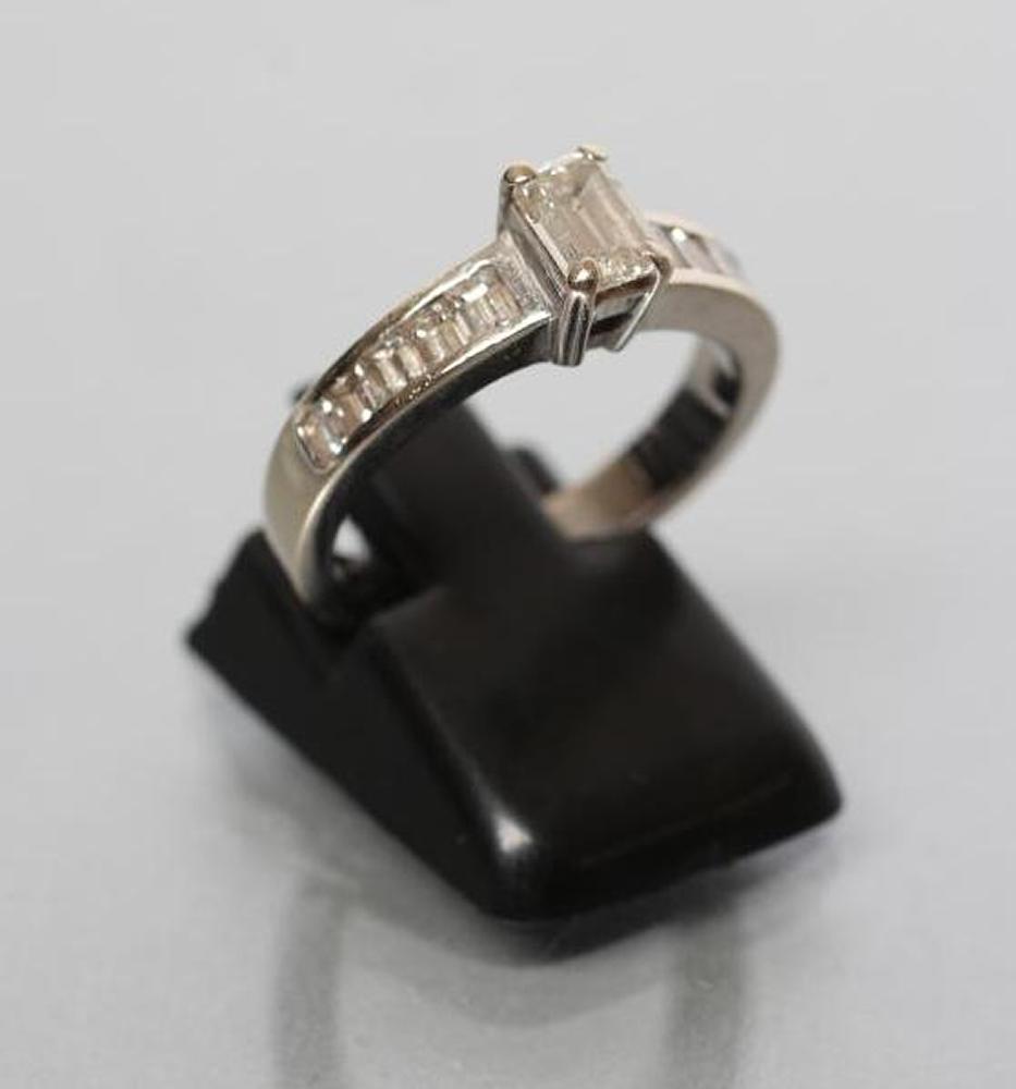 A DIAMOND RING, the baguette cut central stone of approximately 0.30cts claw set to shoulders each