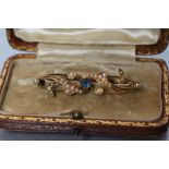 A LATE VICTORIAN BROOCH centred by an open back collet set round sapphire within seed pearl set