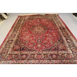 A PERSIAN CARPET, 20th century, the red field with central floral gul in navy blue, green and