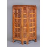 AN EARLY ROBERT THOMPSON ADZED OAK CUPBOARD, c.1918, of canted multi panelled form, the ledge back