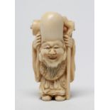 A JAPANESE IVORY NETSUKE, Meiji period, carved as Fukurokuju, holding a staff with a scroll on his