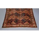 A WEST PERSIAN TRIBAL RUG, the navy field with repeating floral gul pattern, the larger guls in red,