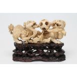 A CHINESE IVORY MODEL carved as a pair of Temple Dogs and their two puppies playing with a puzzle