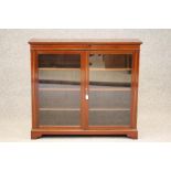 AN EDWARDIAN MAHOGANY BOOKCASE of shallow oblong form, crossbanded with stringing, moulded cornice