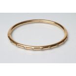A STIFF HINGED BANGLE, of cylindrical section, the upper section set with nine small diamonds,