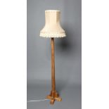 A PETER HEAP ADZED OAK STANDARD LAMP, the faceted tapering stem on stepped cruciform base, carved