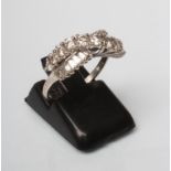 A DIAMOND RING crossover set with eleven graduated brilliant cut stones over fourteen small