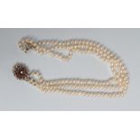 A TRIPLE STRAND CULTURED PEARL NECKLACE, the knotted pearls set to an unmarked white metal open