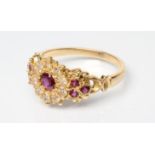 A RUBY AND DIAMOND CLUSTER DRESS RING, the central facet cut ruby within a border of ten round
