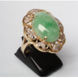 A COCKTAIL RING, the oval cabochon polished jadeite panel claw set to an open floriform border set