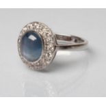 A SAPPHIRE AND DIAMOND DRESS RING, the oval cabochon polished sapphire open back collet set to a