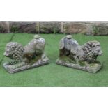 A PAIR OF COMPOSITE STONE LIONS COUCHANT, modelled squatting on their front legs, raised on