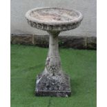A COMPOSITE STONE BIRD BATH, the shallow bowl with lotus leaf edge moulding, raised on tapering stem